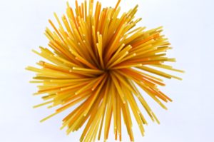 Un mazzo di spaghetti fotografati dall'alto di due colorazioni: normale giallo e arancione